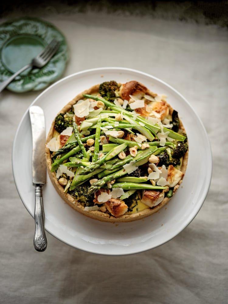 Sparris, purjolök, broccoli och chèvreost fyller pajen som toppas med mer sparris, hasselnötter och parmesan.