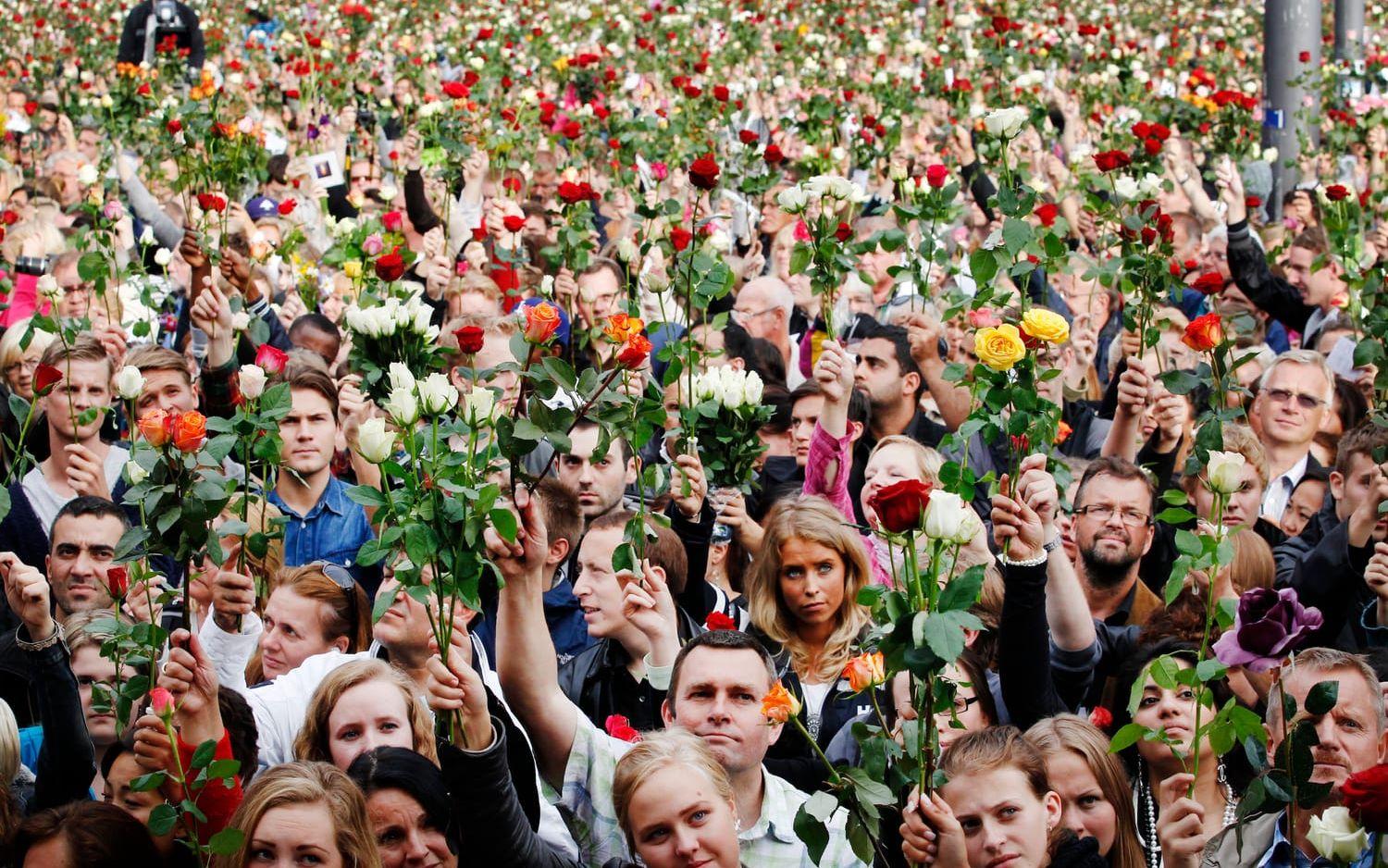 Bild: Erland Aas Folk lyfter rosor mot skyn under minnesceremonin på Rådhusplatsen. 