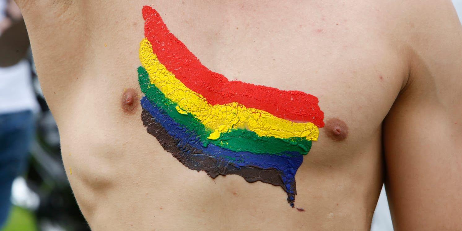 En man med Pride-flaggan målad på bröstet.