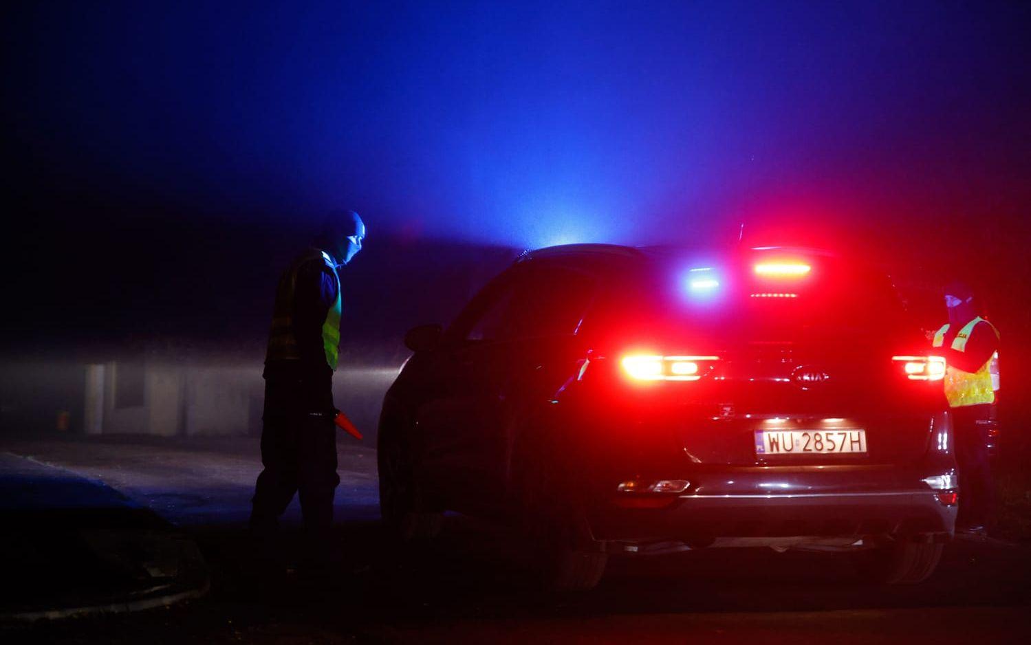 En polisanställd kontrollerar en bil som anländer till nedslagsplatsen i Przewodów.
