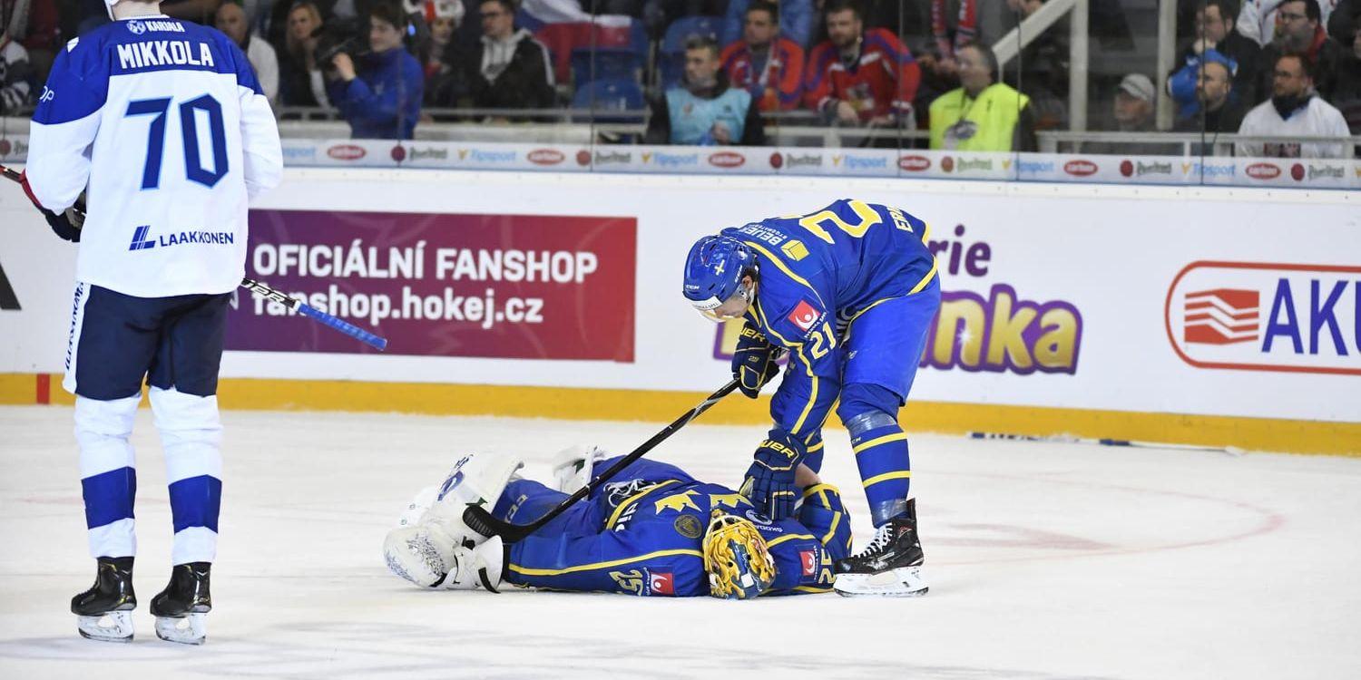 Sveriges målvakt Jacob Markström ligger kvar på isen efter en hård finländsk tackling.