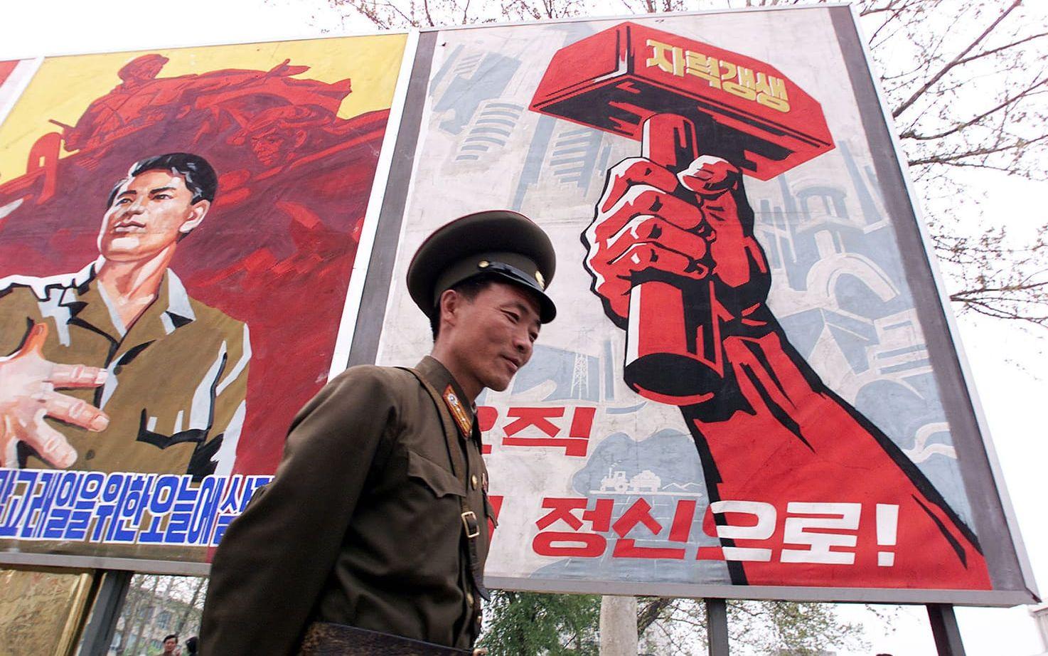 Nordkoreansk soldat poserar vid propagandatavla i Pyongyang. Bild: TT