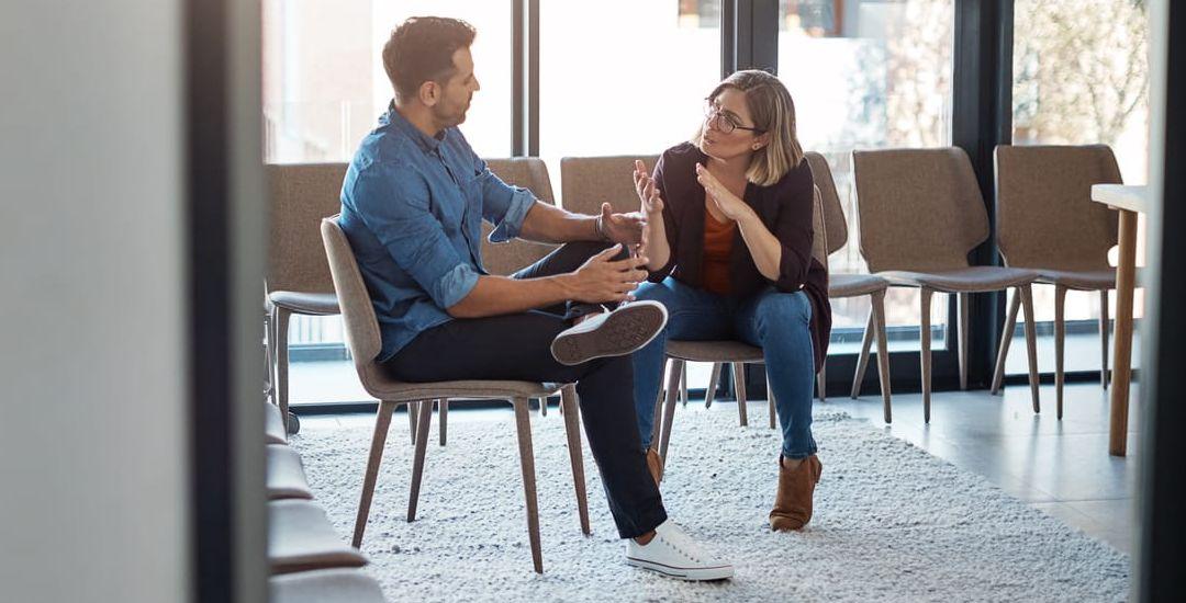 Två arbetskollegor sitter och samtalar med varandra 